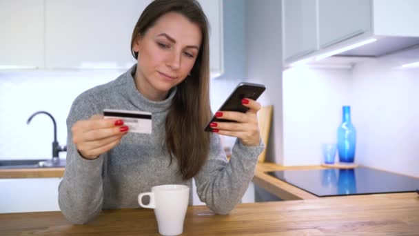 Женщина производит онлайн оплату дома с помощью кредитной карты и смартфона — стоковое видео