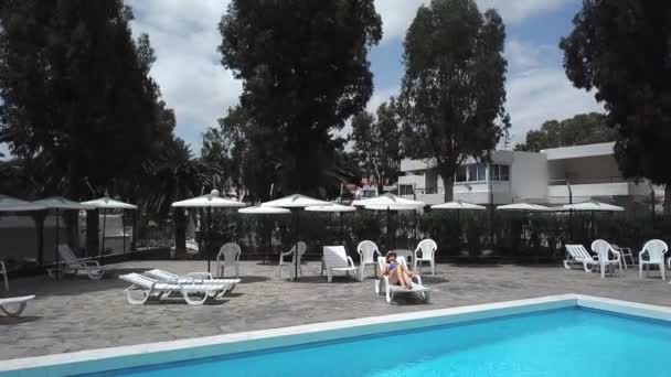 Vista desde arriba como una mujer en traje de baño azul tomando el sol en una tumbona junto a la piscina en un hotel, en una villa o en un apartamento — Vídeos de Stock