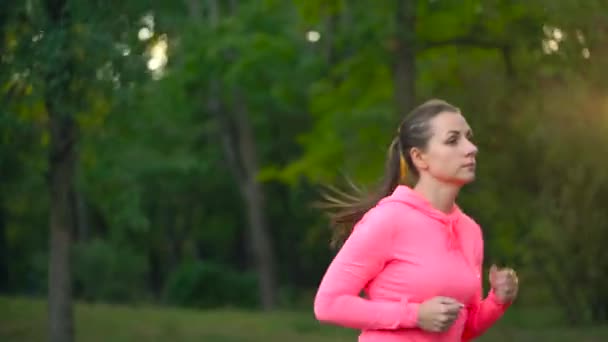 Zbliżenie kobieta działa przez jesienny park o zachodzie słońca — Wideo stockowe