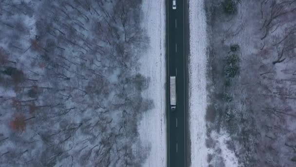 Flygfoto över trafik på vägen passerar genom skogen vintern i hårt väder — Stockvideo