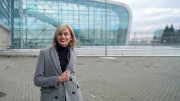 Szőke lány tekercs egy bőröndöt a repülőtér terminál — Stock videók