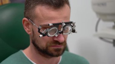 Adam bir göz doktoruna resepsiyonda. Göz muayenesinde ve gözlük lens seçimi