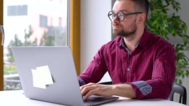 Evde office oturan ve bir dizüstü bilgisayar üzerinde çalışan bardaklarda beared adam