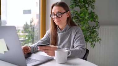 Kadın evde laptop bir kredi kartı ile online ödeme yapar