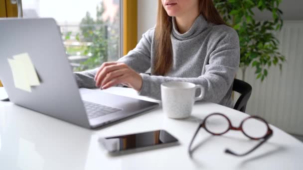 Schöne Frau sitzt zu Hause im Büro und arbeitet an einem Laptop — Stockvideo