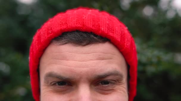 Retrato de um homem em um boné vermelho em tempo nevado ao ar livre — Vídeo de Stock