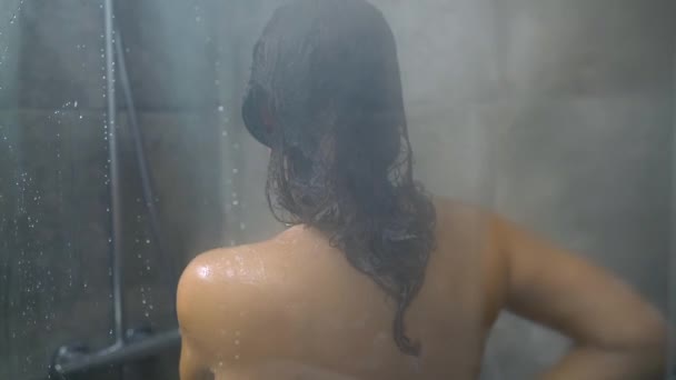 Femme se lave les cheveux, les épaules, les bras et le dos sous la douche. Soins capillaires, concept beauté et bien-être. Mouvement lent — Video