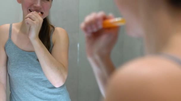 Una mujer guapa lavándose los dientes en un baño por la mañana. Higiene matinal . — Vídeo de stock