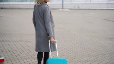 Sarışın kız terminal - arka görünümünden yakınındaki bir çanta alır