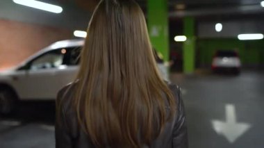 Kadın arabasına gider, kapıyı açar ve içinde oturur