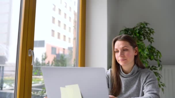 Schöne Frau sitzt zu Hause im Büro und arbeitet an einem Laptop — Stockvideo