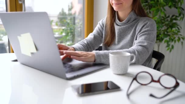 Schöne Frau sitzt zu Hause im Büro und arbeitet an einem Laptop — Stockvideo