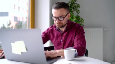 Evde office oturan ve bir dizüstü bilgisayar üzerinde çalışan bardaklarda beared adam