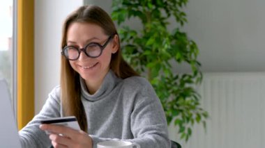 Kadın evde laptop bir kredi kartı ile online ödeme yapar