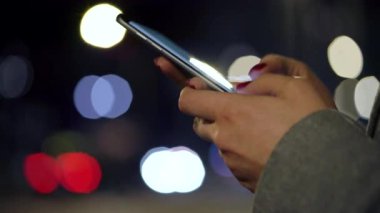 Bulanık şehir ışıkları özgeçmişlerine Smartphone kullanarak eller