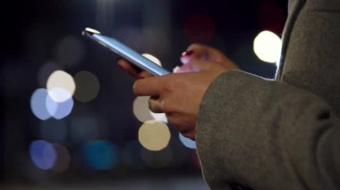 Bulanık şehir ışıkları özgeçmişlerine Smartphone kullanarak eller