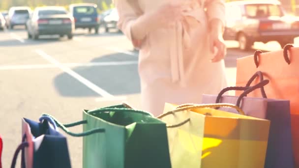Piękna dziewczyna odbiera torby na zakupy z bagażnika samochodu, zamyka go i pozostawia — Wideo stockowe