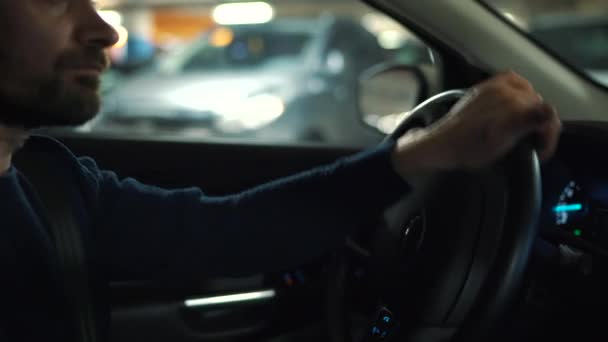 Homem está dirigindo carro através de um estacionamento e está à procura de um lugar para estacionar — Vídeo de Stock