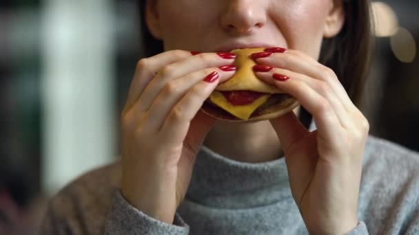 Mujer come una hamburguesa en un café — Vídeos de Stock