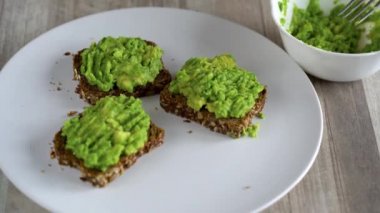 Kızarmış ekmek ve tuz ve baharat serpin püresi avokado yayılıyor. Sağlıklı vejetaryen Kahvaltı.