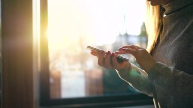 Batan güneşin bulanık cityscape karşı Smartphone kullanarak eller