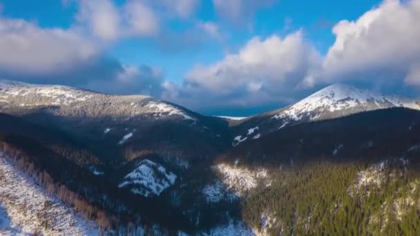 Hiper upływ chmur, przebiegając na niebieski niebo niesamowity krajobraz wysokiej ośnieżonych gór i lasu iglastego na stokach — Wideo stockowe