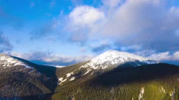 Hyper zánik mraky běží na modrou oblohu nad úžasnou krajinu vysokých zasněžených hor a jehličnaté lesy na svazích — Stock video