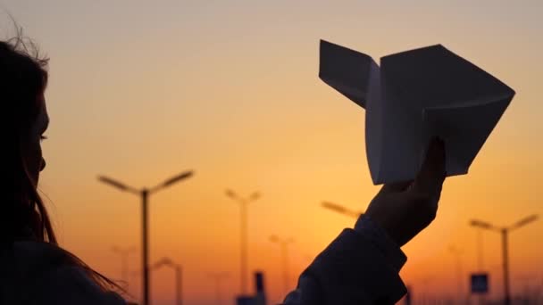 Γυναίκα εγκαινιάζει αεροπλάνο χαρτί ηλιοβασίλεμα φόντο. Έννοια της που θέλουν να πάνε διακοπές ή ταξίδια. Αργή κίνηση — Αρχείο Βίντεο