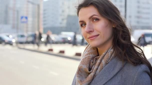 Retrato de una mujer con un peinado y maquillaje neutro en un primer plano de fondo de ciudad — Vídeo de stock