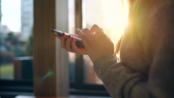 Manos femeninas usando smartphone contra un paisaje urbano borroso al atardecer — Vídeos de Stock