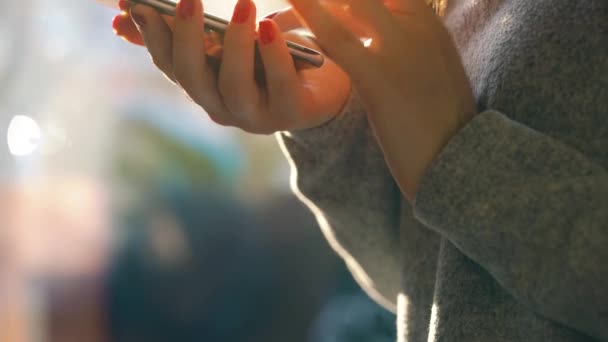 Γυναικεία χέρια χρησιμοποιώντας smartphone ενάντια σε μια θολή αστικό τοπίο στη δύση του ήλιου — Αρχείο Βίντεο