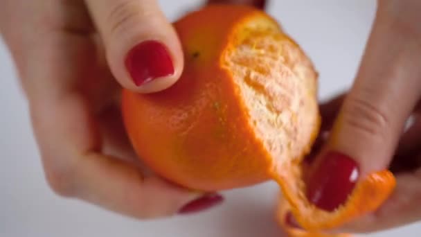Női kéz húzza a héj, a mandarin, mandarin szeletek kupacban találhatók a lemez — Stock videók