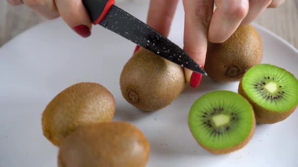 Female hands cut the kiwi with a knife, close up — Stock Video