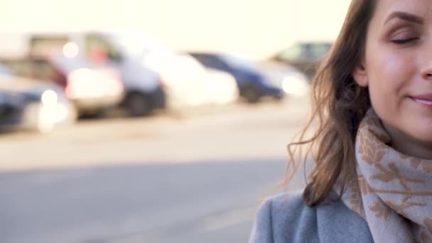 Retrato de uma mulher com um penteado e maquiagem neutra em um close-up de fundo da cidade. Moldura metade da cara. Tráfego em segundo plano — Vídeo de Stock