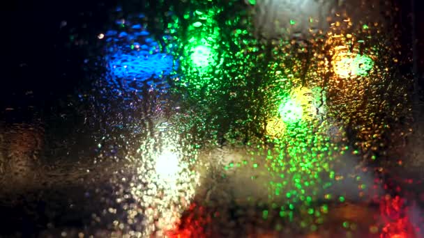 Close up rain drops on car window glass with blurred night city car lights bokeh as background — Stock Video