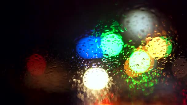 Close up rain drops on car window glass with blurred night city car lights bokeh as background — Stock Video