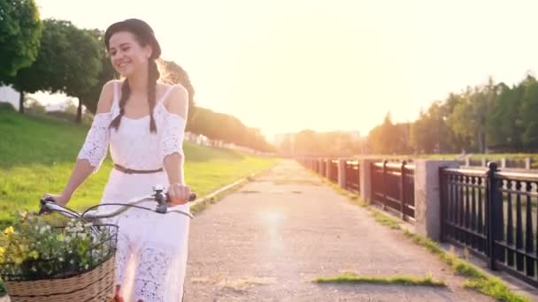 Jovem bela mulher andando de bicicleta ao pôr do sol — Vídeo de Stock