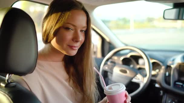 Mooi vrolijk meisje zit in de auto, drinken koffie en lacht — Stockvideo