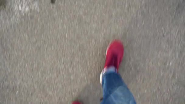 Ovanifrån av mens ben i röda sneakers promenader på asfalt — Stockvideo