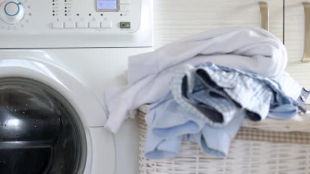 Pranie jest prane w pralce, a czyste rzeczy są na kosz w pobliżu. — Wideo stockowe