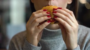 Kadın bir kafede hamburger yiyor