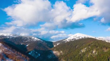 Bulutların üzerinde yüksek karlı dağlar ve iğne yapraklı orman yamaçlarda harika manzara mavi gökyüzü üzerinde çalışan hiper sukut