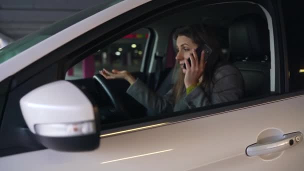 Kvinnan är arg och upprörd på ratten, eftersom sin bil gick sönder. Hon försöker få hjälp via telefon. — Stockvideo