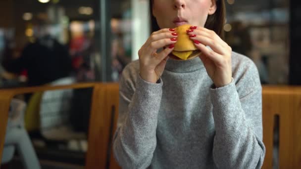 Mujer come una hamburguesa en un café — Vídeos de Stock