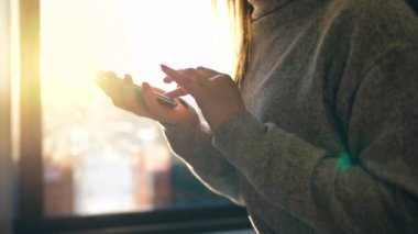 Batan güneşin bulanık cityscape karşı Smartphone kullanarak eller
