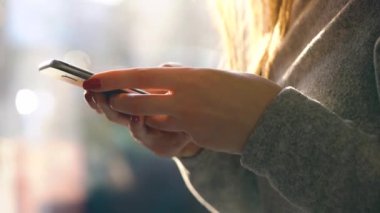 Batan güneşin bulanık cityscape karşı Smartphone kullanarak eller