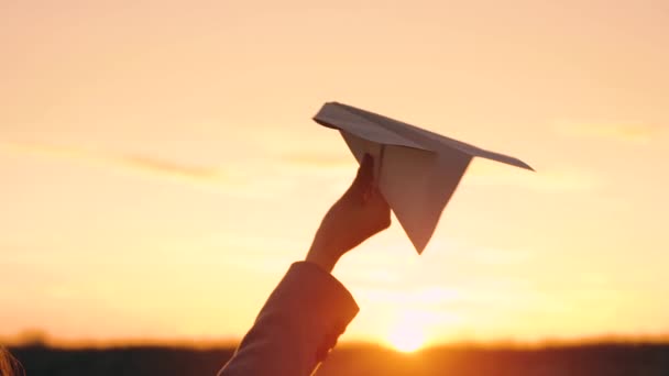 Mujer lanza avión de papel contra fondo del atardecer. Concepto de querer ir de vacaciones o de viaje. Movimiento lento — Vídeos de Stock