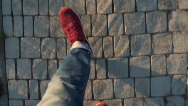 Ovanifrån av mens ben i röda sneakers promenader längs trottoaren — Stockvideo