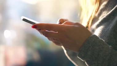 Batan güneşin bulanık cityscape karşı Smartphone kullanarak eller