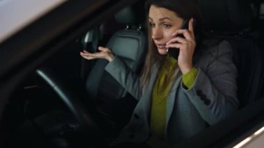 Kadın kızgın ve üzgün direksiyonda, arabası bozuldu çünkü. Telefonla Yardım almak çalışıyor.